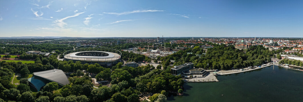 Hanover, Germany - 12 July 2026: Aerial view of Maschsee and surrounding urban landscape, featuring Heinz von Heiden Arena, lush green parks, and city skyline under clear blue sky.