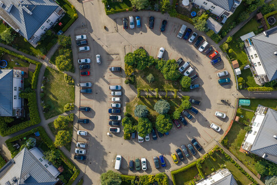 Aerial view of a residential parking area with numerous cars parked in a circular layout surrounded by houses and greenery in Pruszkow, Masovian Voivodeship, Poland.