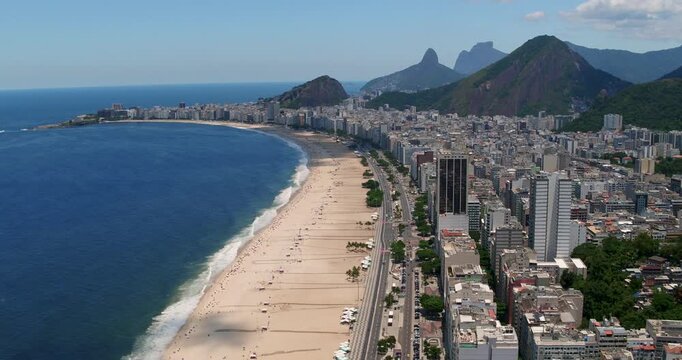 Aerial view of Copacabana Beach with its iconic promenade, sandy coastline, and urban skyline against the backdrop of mountains in Rio de Janeiro, State of Rio de Janeiro, Brazil.