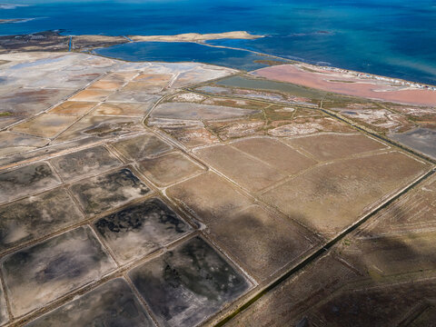 Aerial view of the decommissioned salt processing plant featuring vast rectangular salt pans, textured earth, and vibrant coastal ponds in Avalon, Victoria, Australia.