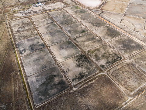 Aerial view of the decommissioned salt processing plant featuring a grid of rectangular evaporation ponds with varying textures and earth tones in Avalon, Victoria, Australia.