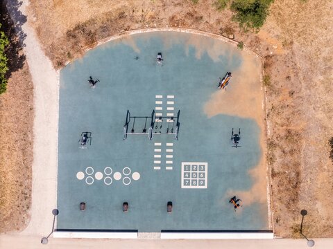 Aerial view of an outdoor fitness area with exercise equipment and painted markings on a rubberized surface in Estoril, Lisbon, Portugal.