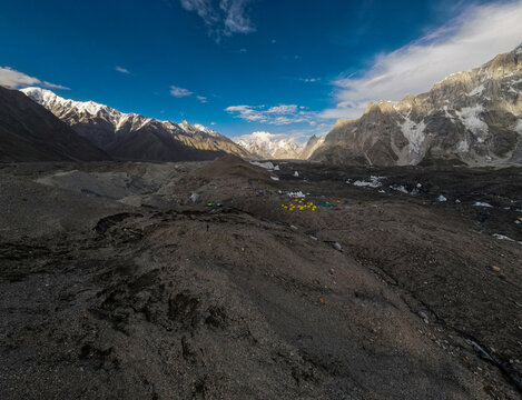 Aerial view of Goro II campsite situated on a rocky glacier moraine surrounded by towering snow-capped peaks in Goro II, Gilgit Baltistan, Pakistan.