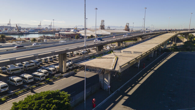 Aerial view of the unfinished Foreshore Freeway Bridge with traffic on the adjacent highway and harbor infrastructure in the background, Cape Town, Western Cape, South Africa.