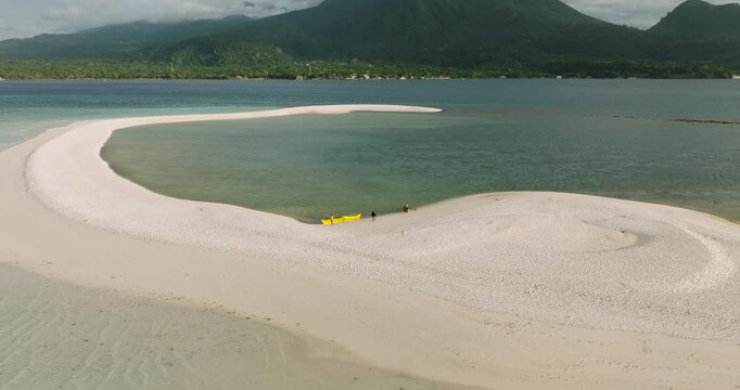 Aerial view of White Island sandbar with turquoise water and a yellow outrigger boat in Mambajao, Camiguin, Philippines.