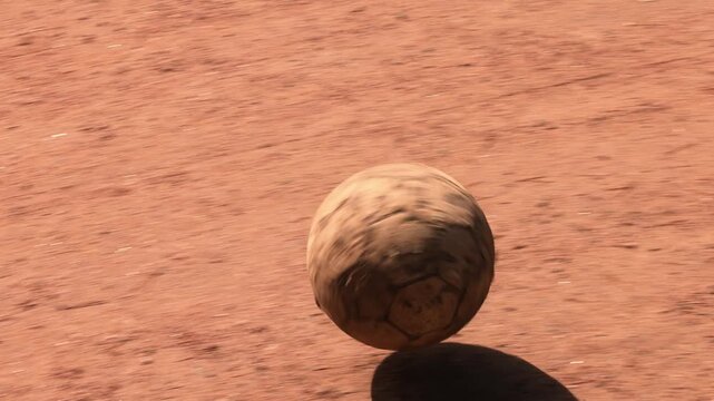 Old worn soccer ball on dusty ground during street football game