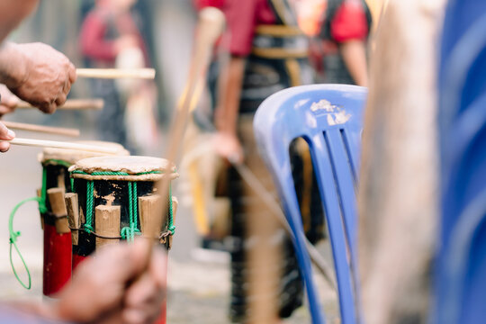Bajawa, Nusa Tenggara Timur, Indonesia - 09 July 2026: View of hands playing traditional drums with sticks during a cultural performance, with blurred figures in traditional garb.
