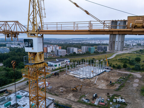Gdansk, Poland - 12 July 2026: Aerial view of a construction site with a yellow tower crane, concrete building frame, and heavy machinery in an urban development area.