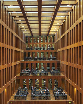 View of the Jacob-und-Wilhelm-Grimm-Zentrum library interior with multi-level reading areas, wooden bookshelves, and students studying under natural light in Berlin, Berlin, Germany.