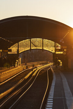 View of a U-Bahn station platform with people waiting for the train under a large arched roof during golden hour in Berlin, Berlin, Germany.