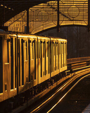 View of a U-Bahn train illuminated by warm golden hour light on the tracks at a station in Berlin, Berlin, Germany.