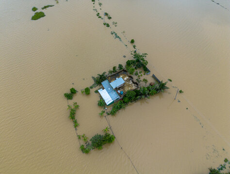 Aerial view of a house isolated by floodwaters with surrounding vegetation and muddy water in Banshkhali Upazila, Chittagong Division, Bangladesh.