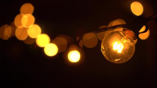 Warm glowing incandescent light bulbs in the night with panoramic camera movement