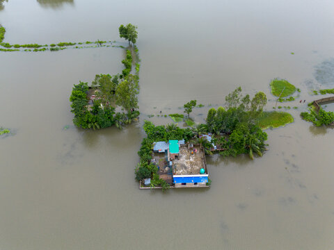 Aerial view of a house surrounded by floodwaters in the rural landscape of Banshkhali Upazila, Chittagong Division, Bangladesh.