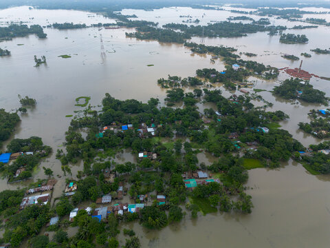 Aerial view of flooded residential area with submerged houses and trees surrounded by muddy water in Banshkhali Upazila, Chittagong Division, Bangladesh.