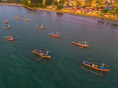 Aerial view of traditional fishing boats floating on the calm sea near the sandy shore of Pantai Panjang Bengkulu in Kecamatan Ratu Agung, Bengkulu, Indonesia.