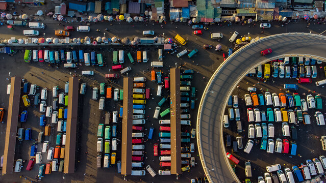 Aerial view of Kwame Nkrumah Circle featuring a busy bus terminal with numerous colorful minibuses and a prominent curved overpass in the urban landscape of Accra, Greater Accra Region, Ghana.