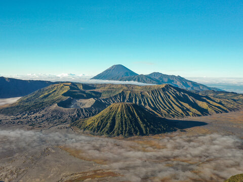 Aerial view of Mount Bromo and Mount Semeru volcanoes rising above a sea of clouds in the Tengger caldera landscape in Tosari, East Java, Indonesia.