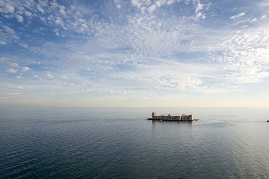 Kizkalesi, Turkiye - 01 November 2025: Aerial view of the historic Maiden's Castle situated on a small island in the Mediterranean Sea under a vast sky with scattered clouds.