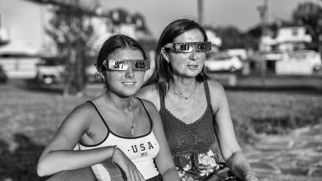 Family observing solar eclipse in park captured in dramatic black and white