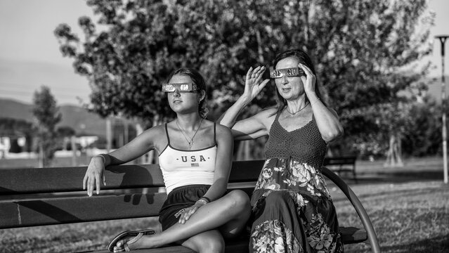 Black and white family silhouette during solar eclipse in natural park landscape