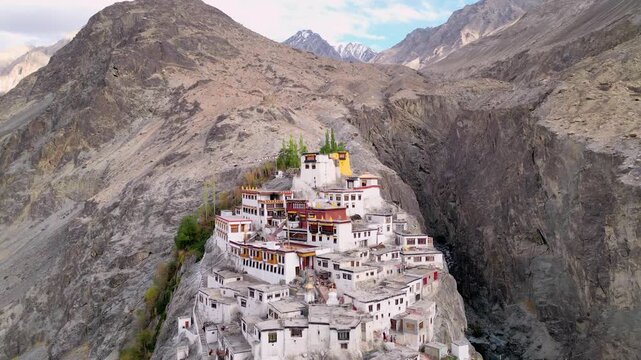 Aerial view of Diskit Monastery perched on a rocky cliff in the Himalayas, featuring white-washed buildings and traditional architecture in Diskit, Ladakh, INDIA.
