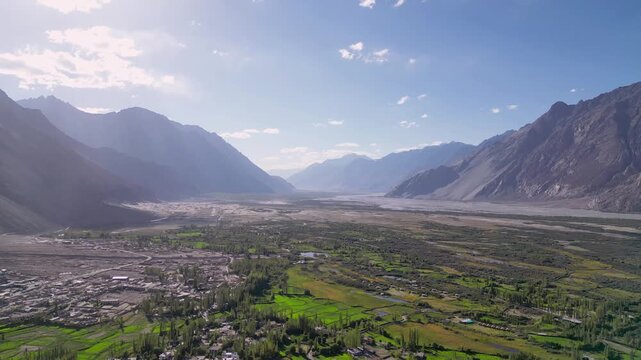 Aerial view of Diskit Monastery nestled in the vast valley of Ladakh with lush green fields and towering mountains under a bright sky in Diskit, Ladakh, INDIA.