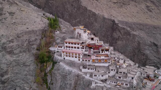 Aerial view of Diskit Monastery perched on a rocky cliffside in the Himalayas with white buildings and traditional architecture in Diskit, Ladakh, INDIA.