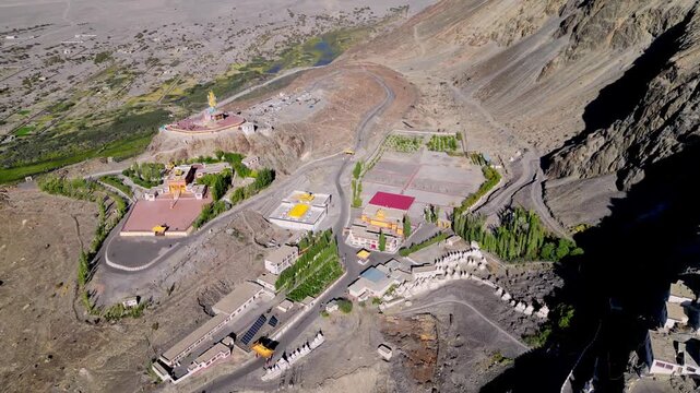 Aerial view of Diskit Monastery surrounded by arid mountain landscapes and winding roads in Diskit, Ladakh, India.