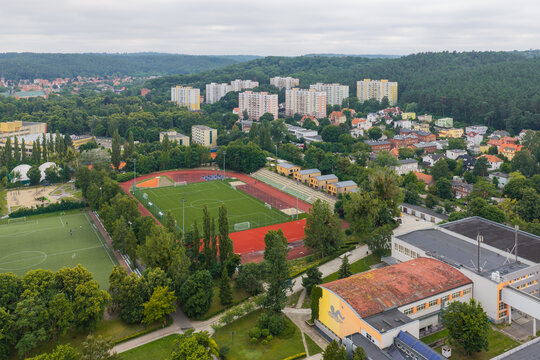 Aerial view of the Oliwa district featuring a soccer field and running track surrounded by trees, apartment blocks, and urban infrastructure in Gdansk, Pomeranian Voivodeship, Poland.