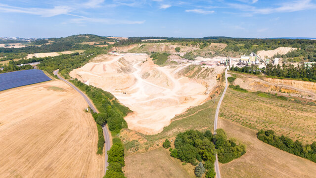 Aerial view of a limestone quarrying operation with processing facilities, exposed earth, and surrounding agricultural fields in Trier-Saarburg, Rhineland-Palatinate, Germany.
