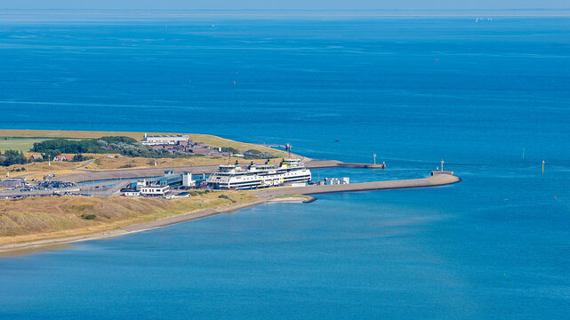 Aerial view of the TESO ferry terminal with a docked ferry boat along the breakwater and the calm blue waters of the Wadden Sea in Den Hoorn Texel, Noord-Holland, Netherlands.