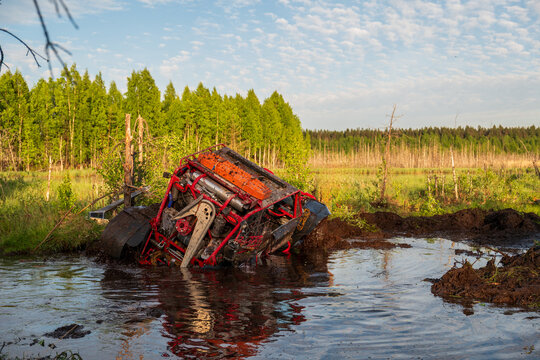 View of a red off-road vehicle stuck in a muddy swamp near the forest edge of Lake Ladoga in Sortavala, Respublika Kareliya, Russia.