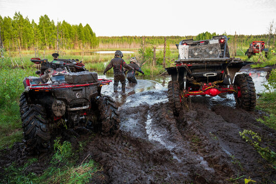 View of two ATVs stuck in deep mud with riders wading through the marshy terrain near Lake Ladoga in Sortavala, Respublika Kareliya, Russia.