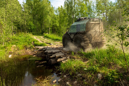 View of an all-terrain vehicle crossing a small wooden log bridge over a stream in a lush forest near Lake Ladoga, Sortavala, Respublika Kareliya, Russia.