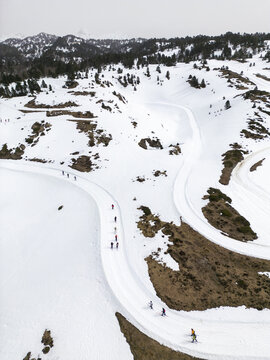 Aerial view of cross-country skiers gliding along a winding snow-covered track through the mountainous landscape of Isaba, Navarre, Spain.