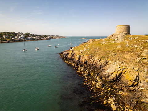 Aerial view of Dalkey Island featuring its historic Martello tower, rugged rocky coastline, and sailboats on the sea near Dublin, County Dublin, Ireland.