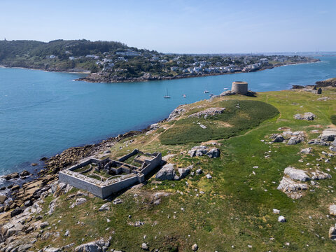 Aerial view of Dalkey Island featuring the historic Martello tower and stone ruins set amidst a grassy landscape and rocky coastline surrounded by the sea in Dublin, County Dublin, Ireland.