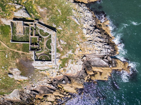 Aerial view of the historic ruins on Dalkey Island, featuring stone walls and foundations set against rugged coastal cliffs and the blue waters of the Irish Sea in Dublin, County Dublin, Ireland.