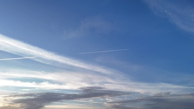 Aerial view of the blue sky with long white airplane contrails stretching across the horizon in Cascais, Lisboa, Portugal.