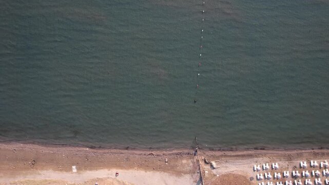 Aerial view of the coastline at Deniz Kizi Beach with calm sea waters and sandy shore in Cesme, Izmir, Turkey.