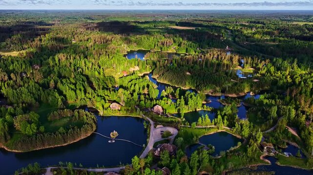 Aerial view of the residential area of Amatciems with its interconnected ponds, lush green forests, and wooden houses in Amatciems, Cesu novads, Latvia.