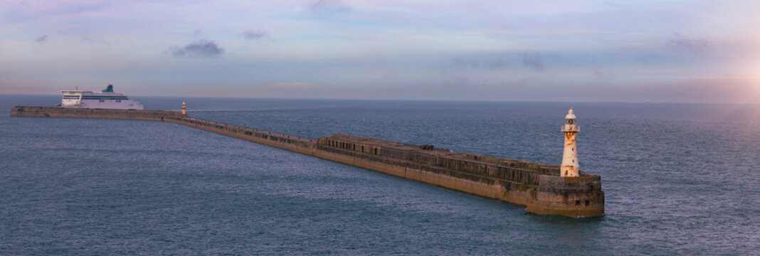 Aerial view of the Admiralty Pier Lighthouse at the end of a long stone breakwater with a ferry approaching the harbour in Dover, England, United Kingdom.