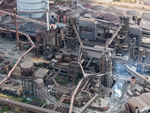 Aerial view of a large industrial steel plant featuring complex piping, blast furnaces, and storage tanks in the United Kingdom.