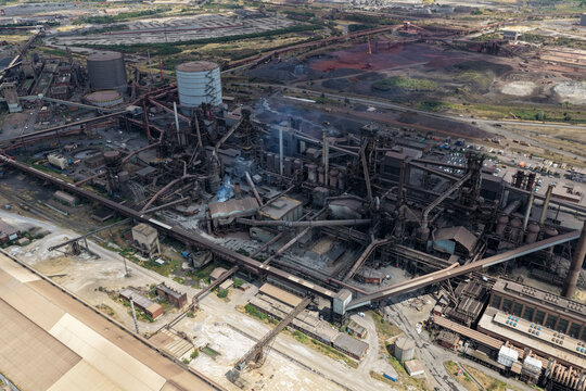Aerial view of the Redcar Blast Furnace industrial complex with intricate steel structures, pipelines, and storage tanks set against a vast landscape in the United Kingdom.