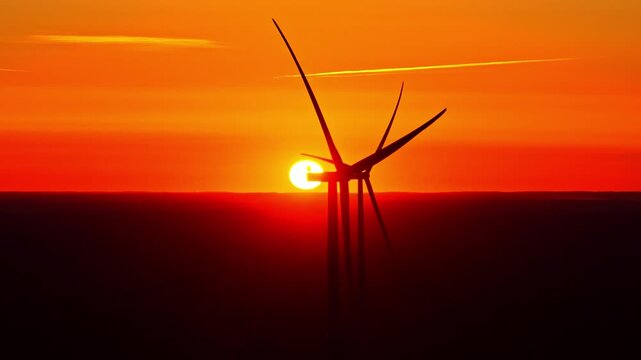 Aerial view of wind turbine silhouette against a vibrant sunset over the peat bog landscape of Kaigu Purvs in Livberze parish, Jelgava Municipality, Latvia.