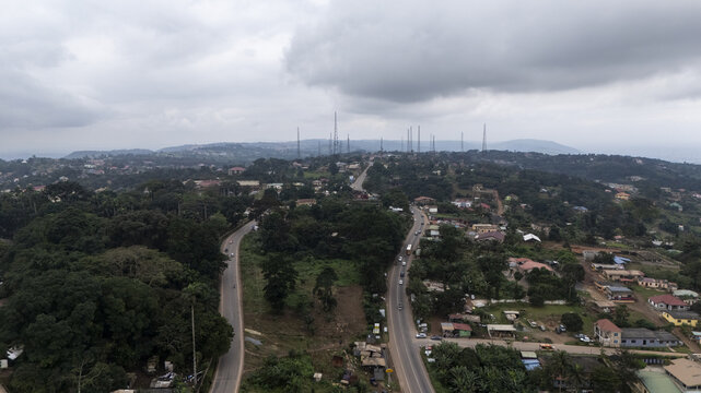 Aerial view of Aburi Botanical Gardens and Park surrounded by lush tropical vegetation, winding roads, and residential buildings under a cloudy sky in Aburi, Eastern Region, Ghana.