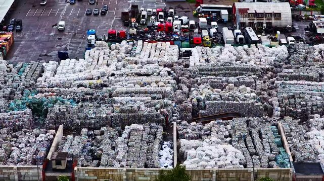 Aerial view of a large recycling facility filled with rows of compressed material bales and parked trucks in Jelgava, Jelgava, Latvia.