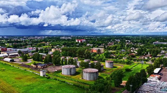 Aerial view of industrial storage tanks surrounded by green fields and urban infrastructure in Jelgava, Jelgava pilseta, Latvia.