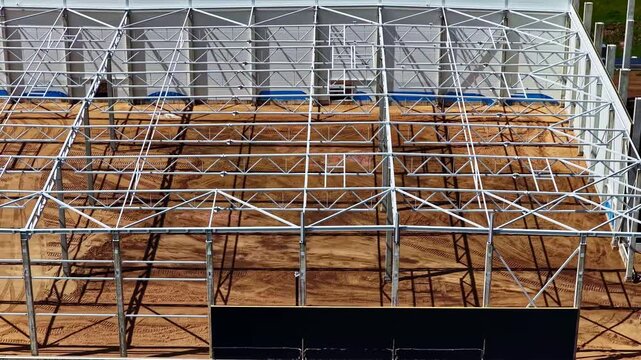 Aerial view of a large metal frame structure under construction on a dirt site in Jelgava, Jelgava pilseta, Latvia.